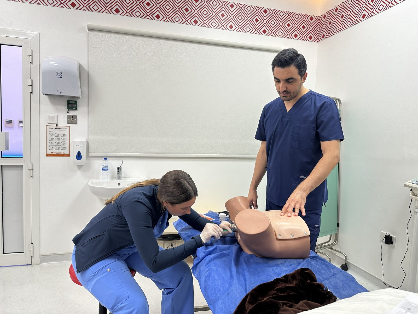 Dr. Alireza Amin supervising a student practising a clinical procedure on a task trainer in a skills classroom