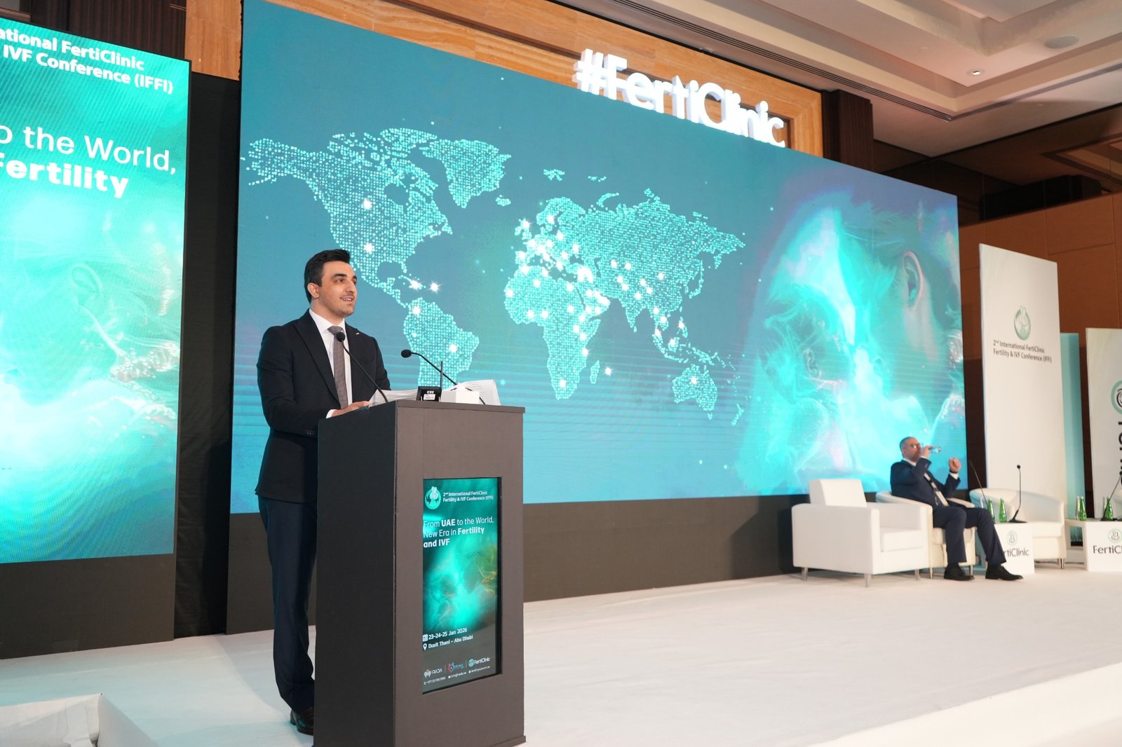 Dr. Alireza Amin speaking at a lectern before the FertiClinic conference backdrop.