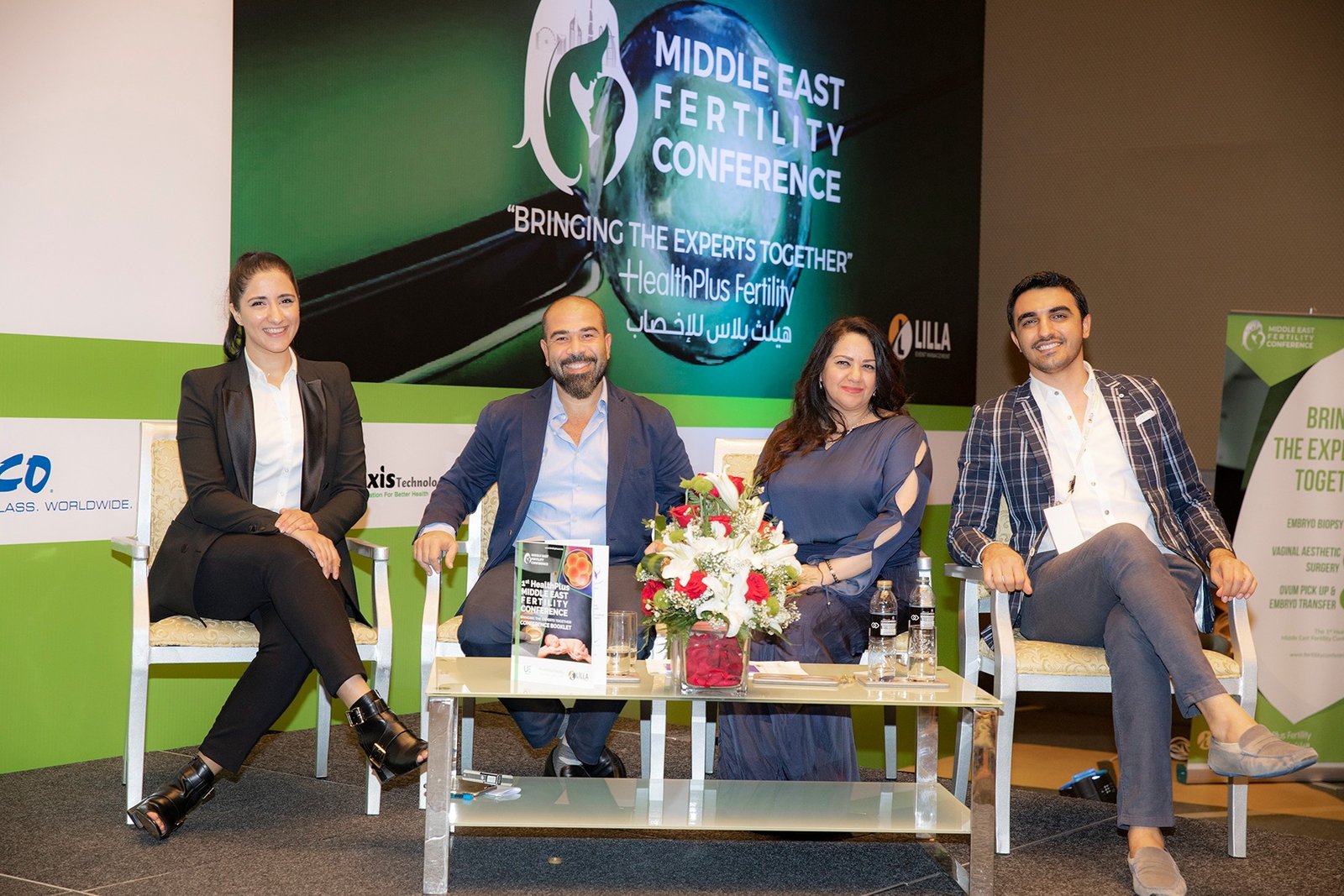 Four people seated in front of the first HealthPlus Middle East Fertility Conference backdrop.