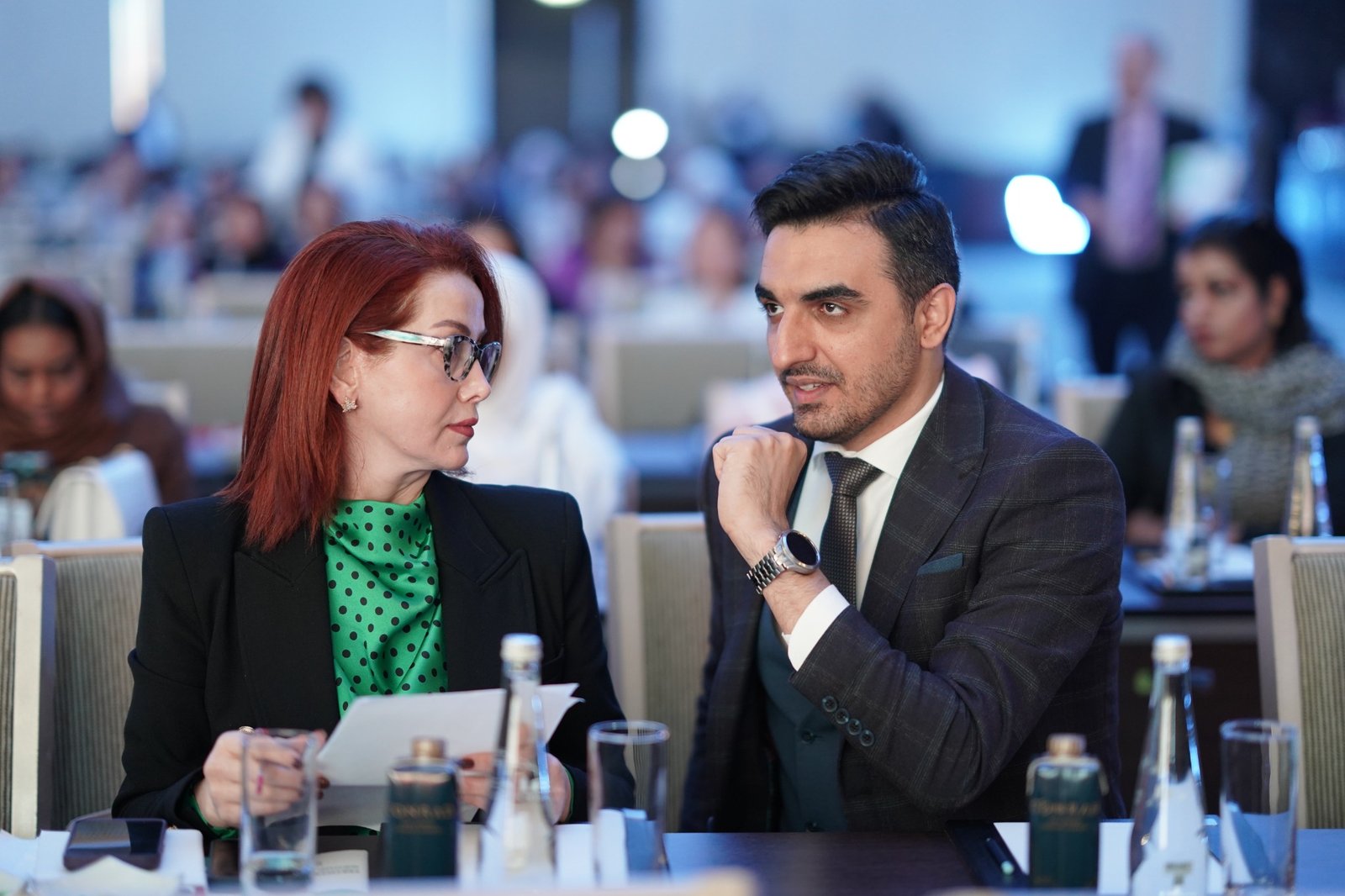 Dr. Alireza Amin in conversation at a conference table, with attendees in the background.