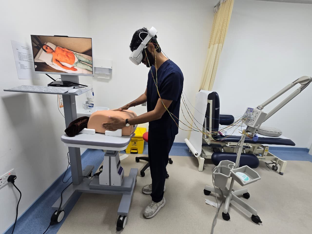 Research setup with a headset, scalp leads, a physical abdominal trainer and simulation monitor
